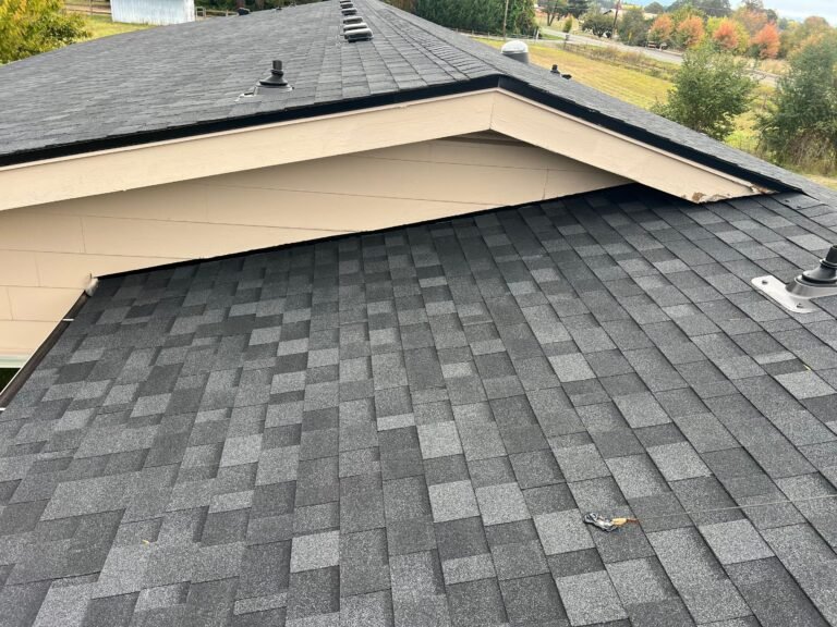 Gable peak and ridge covered in new gray shingles, with small vents along the ridgeline.