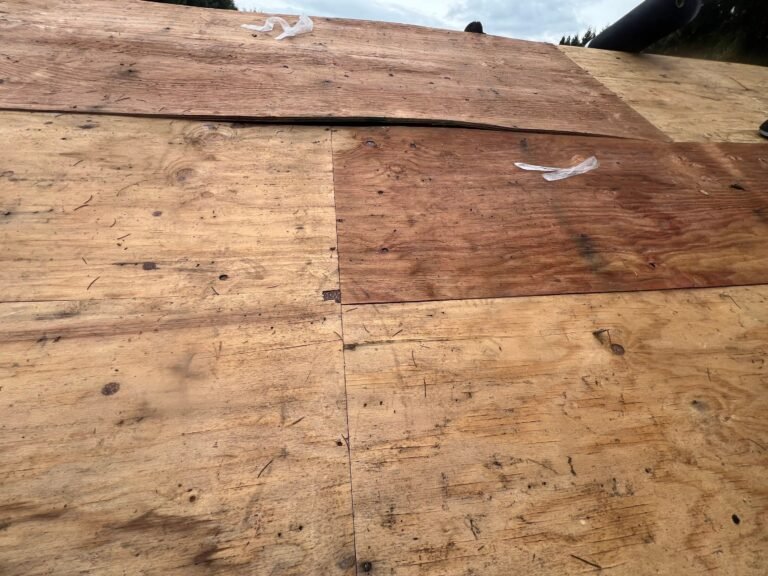 Roof decking after tear-off, with sections of plywood in varying shades and a few areas of replaced sheathing.