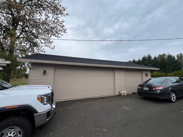 Newly roofed ranch-style home with a large attached garage, a white pickup truck and a dark sedan parked on the asphalt driveway.